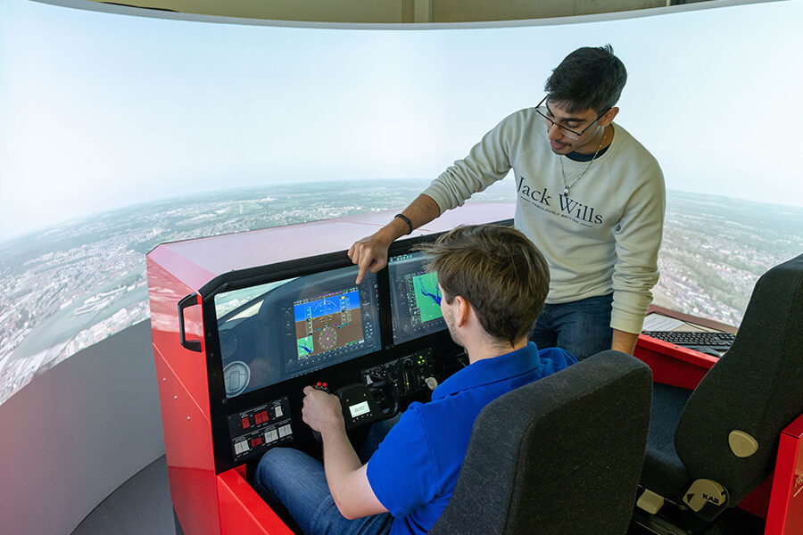 Man using a flight simulator with another man watching